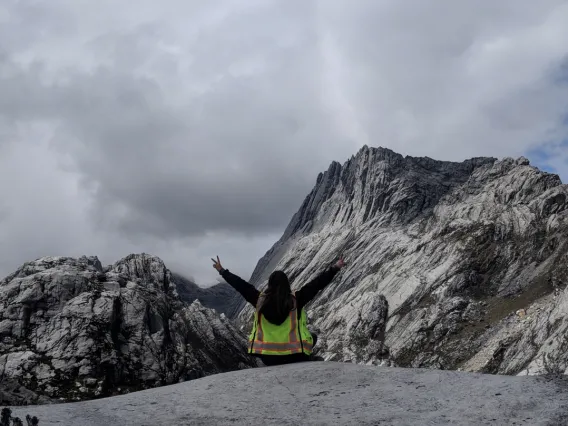 Worker in PPE poses in front of a mountain range