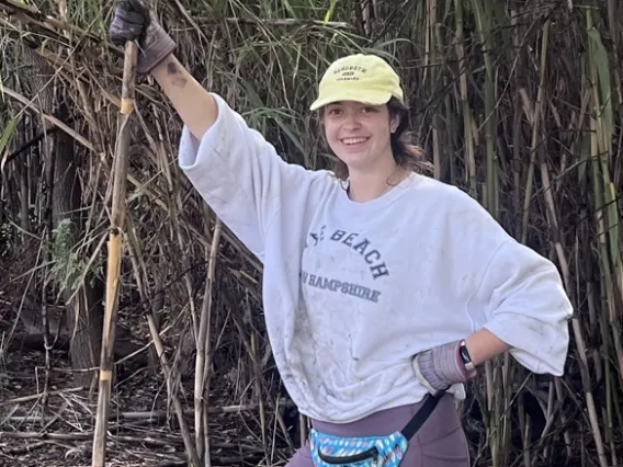 Nicole Collins stands next to foliage while volunteering.