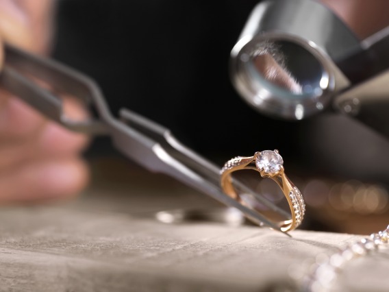 Close-up view of a diamond ring being examined using a jeweler's loupe