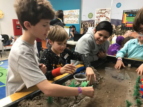 Kids playing with dirt and soil with a replica of a bioma