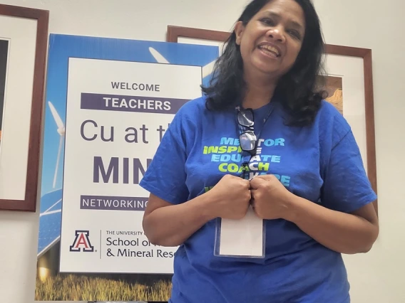 smiling teacher in front of sign