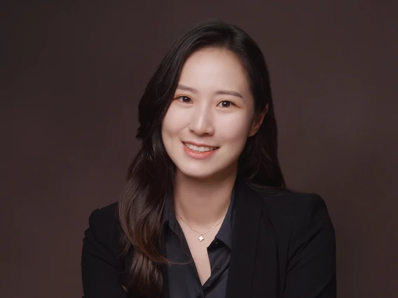 headshot of person with long hair, wearing black shirt and blazer