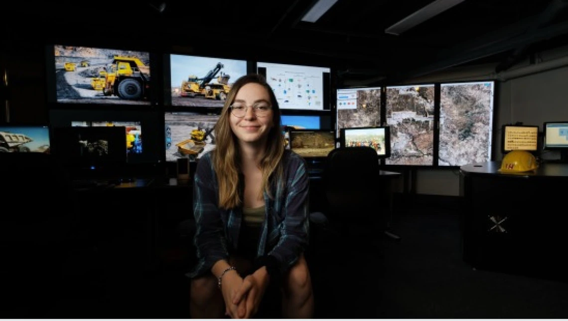 smiling student with tv screens in background