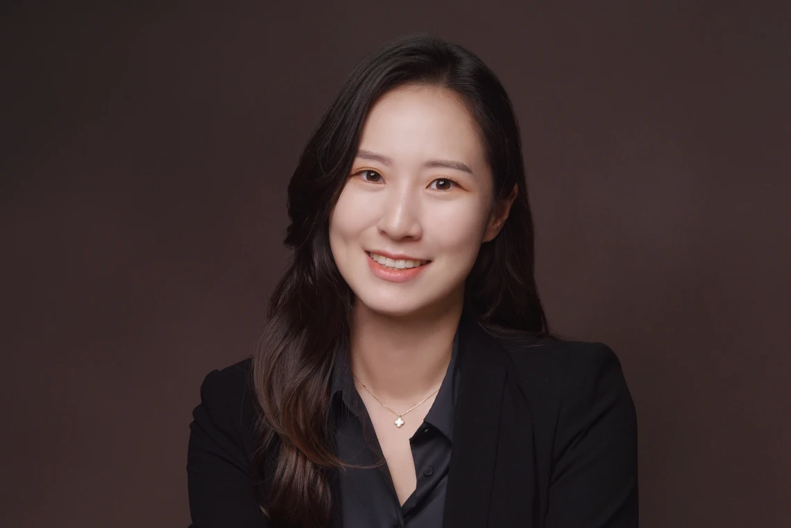 headshot of person with long hair, wearing black shirt and blazer