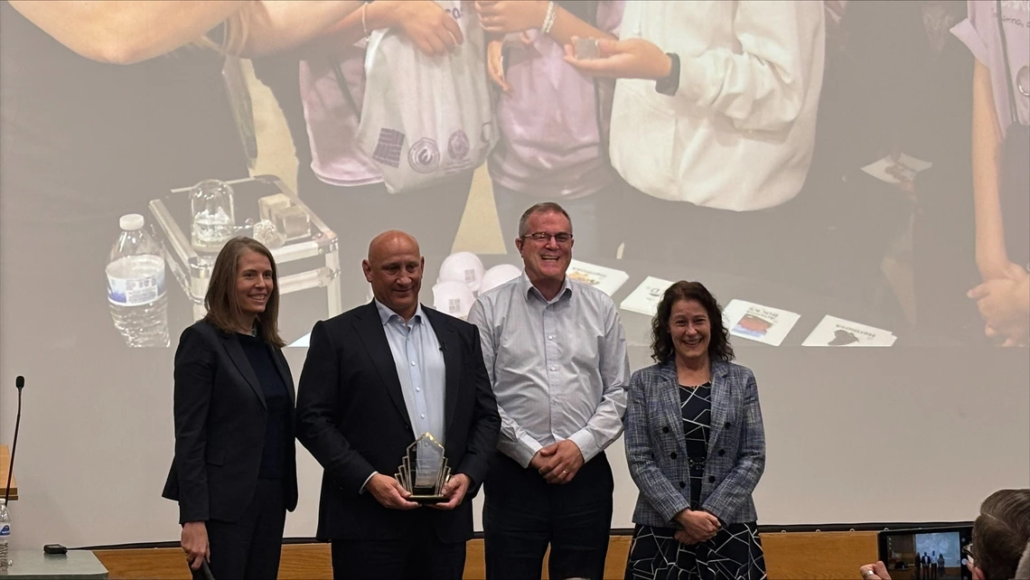 Four people stand in front of a screen.