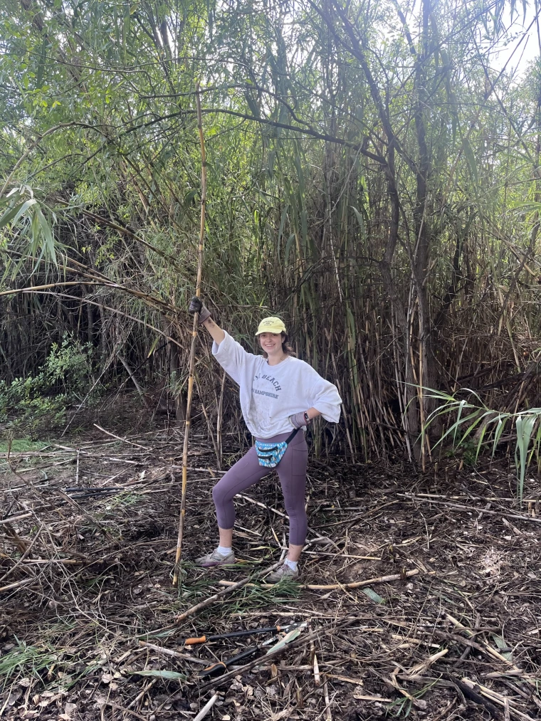 Nicole Collins stands next to foliage while volunteering.