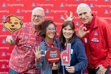 four people smiling, some holding Univ of AZ SWAG