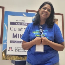 smiling teacher in front of sign