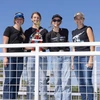 four people standing behind fence, one holding a trophy